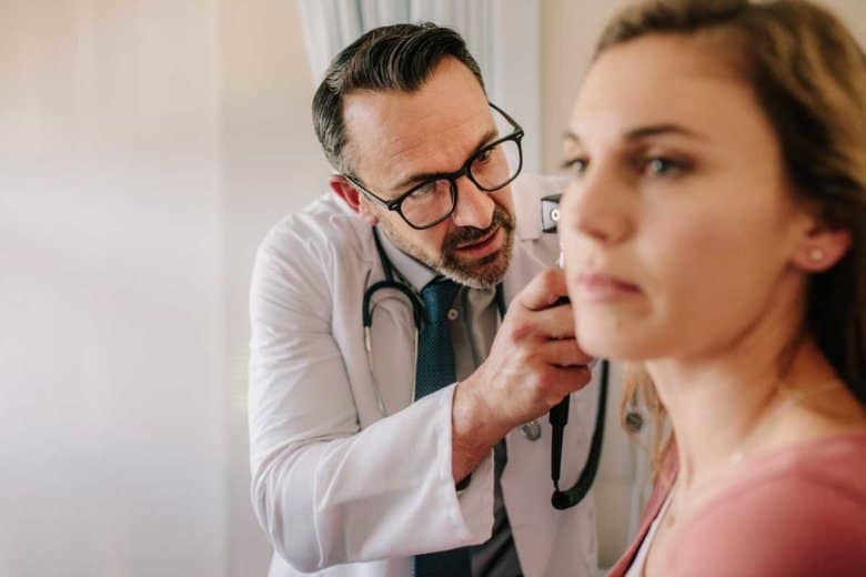 Ein HNO-Arzt untersucht das Ohr einer Patientin