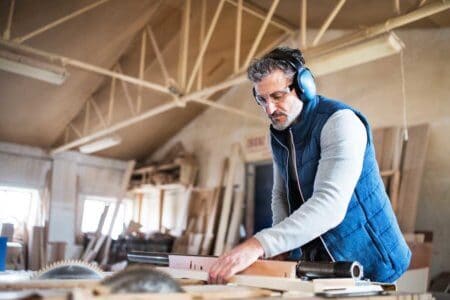 Ein Schreiner arbeitet in seiner Werkstatt mit Gehörschutz